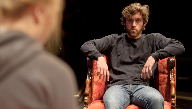 an actor in an ornate chair staring intently at another actor
