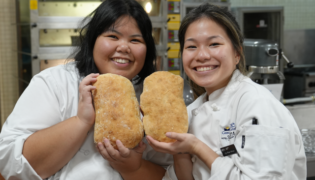 culinary students smiling and showing off bread they've baked