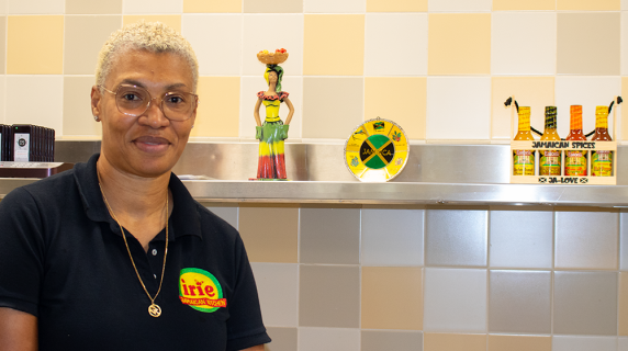 Chef Barbara posing in front of Jamaican decorations at Irie Kitchen on campus