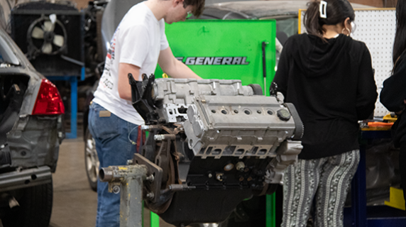two high school students examining an engine
