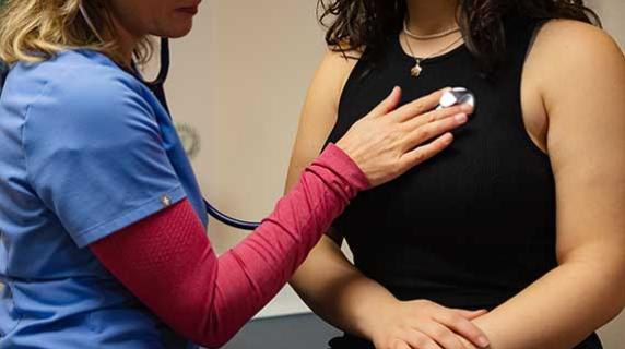 a health practicioner listens to a patient's heartbeat with a stethoscope 