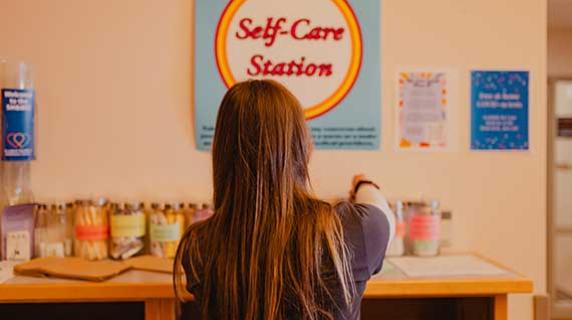 a woman in scrubs accessing the self care station at the health clinic