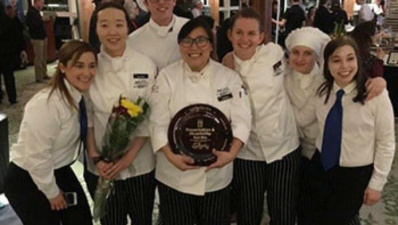 image of seven smiling culinary students with award and flowers