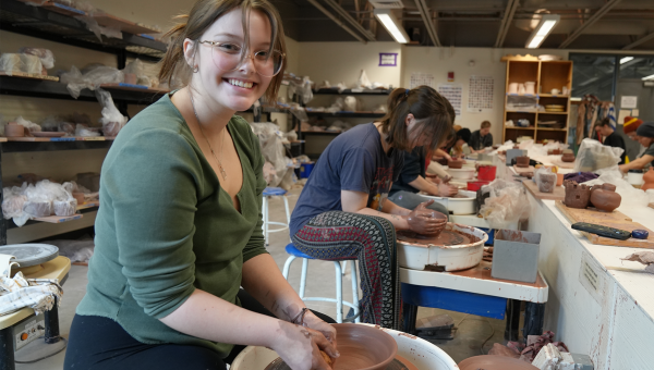 art student throwing clay at a wheel
