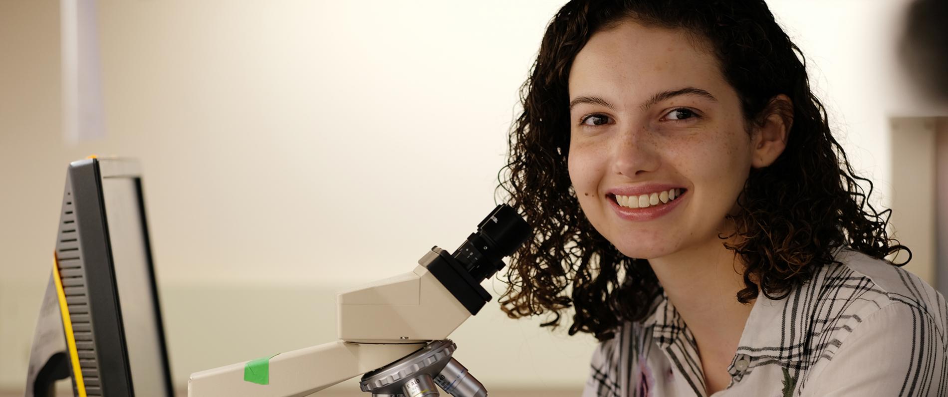 Student with a microscope and a computer