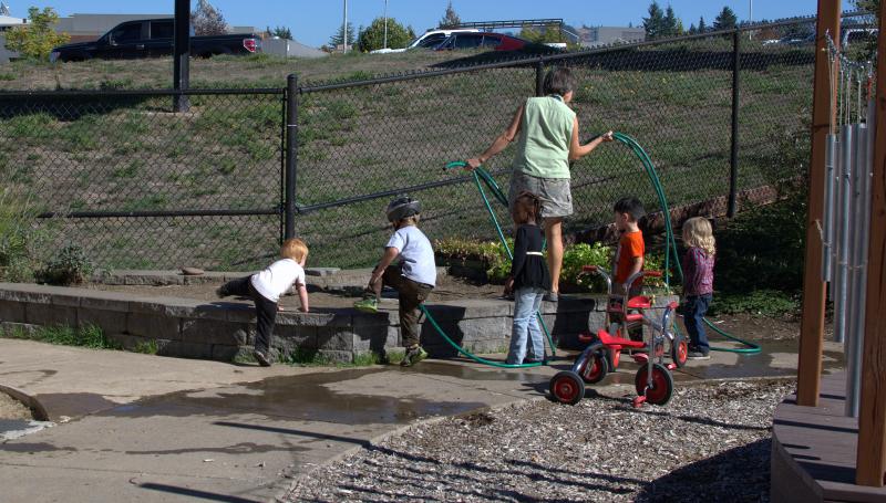teacher and students playing with water outside