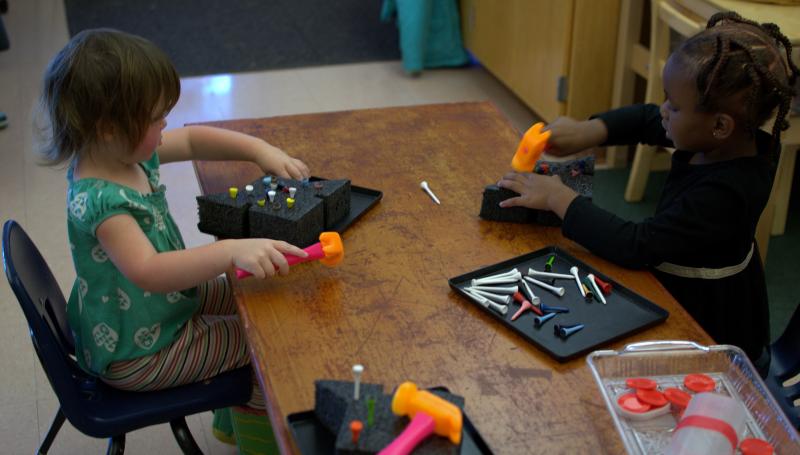 kids playing with plastic nails and a hammer