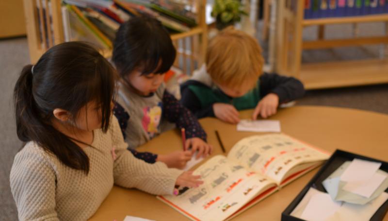 Kids learning to draw from a book together