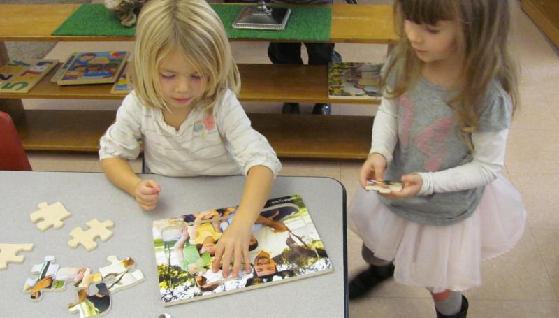 Kids putting together a puzzle.