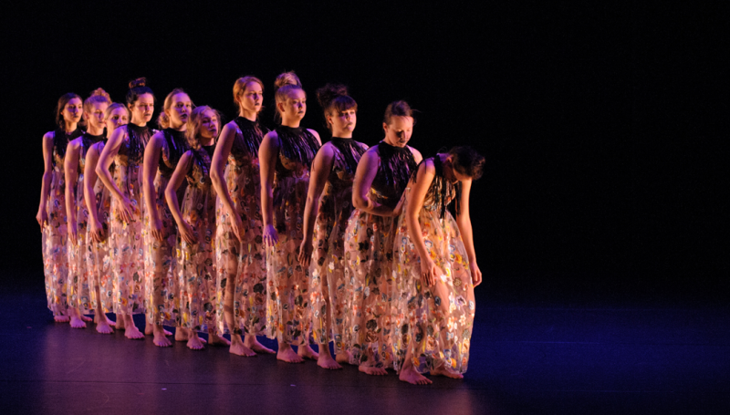 dancers in a line on a dark stage