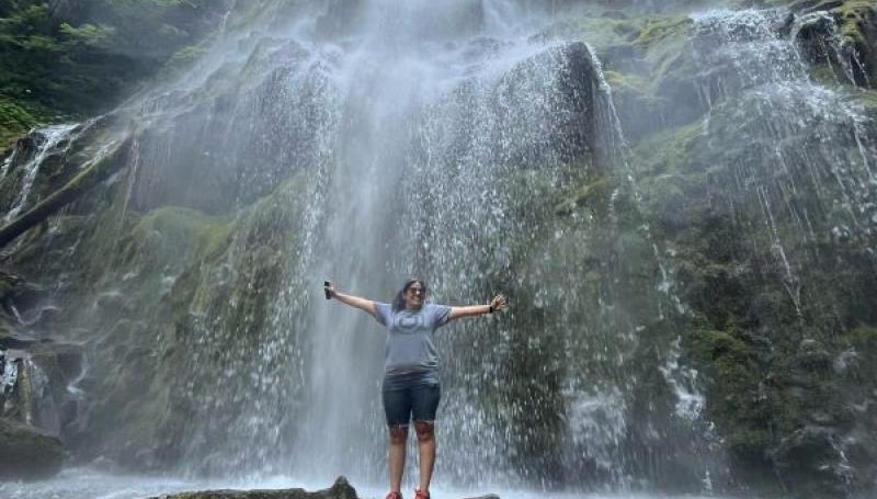 Admissions staff Rosa Maria posing in front of a waterfall