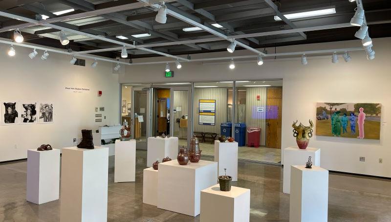 A bright art gallery room filled with student art of various mediums