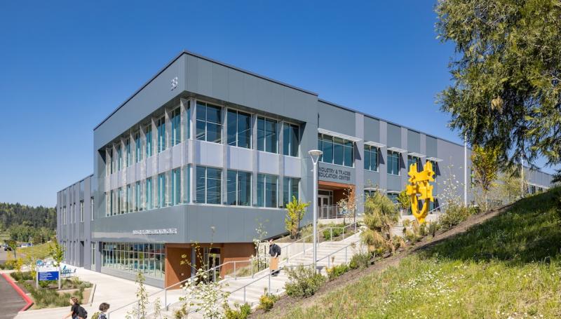 The exterior of the ITEC building on a sunny day with students and the bright yellow statue in front