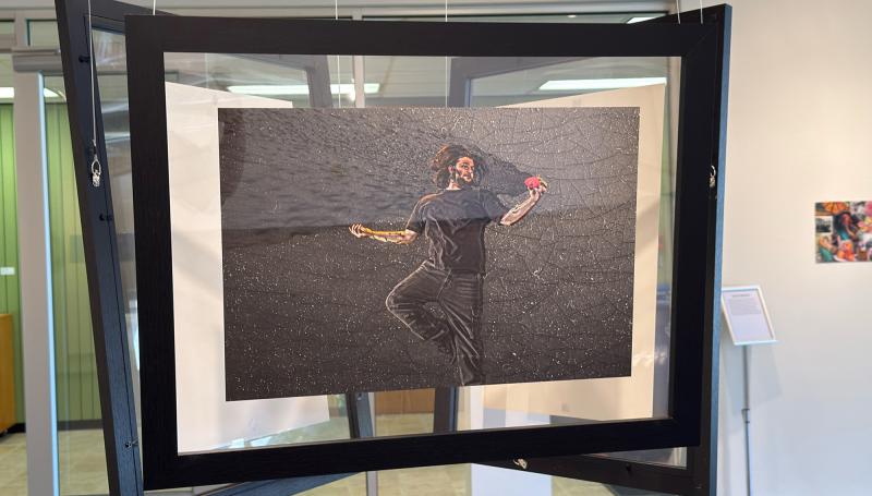 a man lying on a dark gray slate examining a small pink object with mist emanating from it