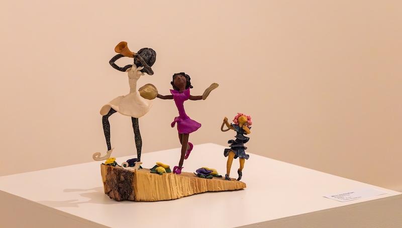 a sculpture of three Black girls playing instruments and wearing billowing dresses by Mira Lea Rinehart