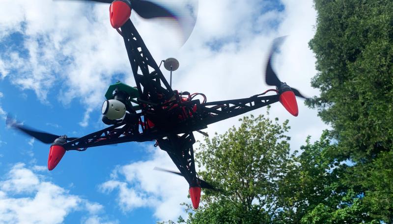 a black and red drone with the sky and tress in the backgroud