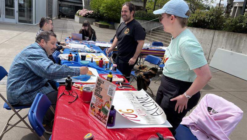 a MEChA event outside the center building where students are happily painting peaceful protest signs