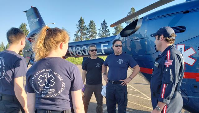 emt students listen to instructor in front of a medical helicopter