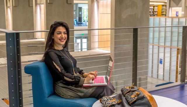a fashionable student smiling as she studies in the library 