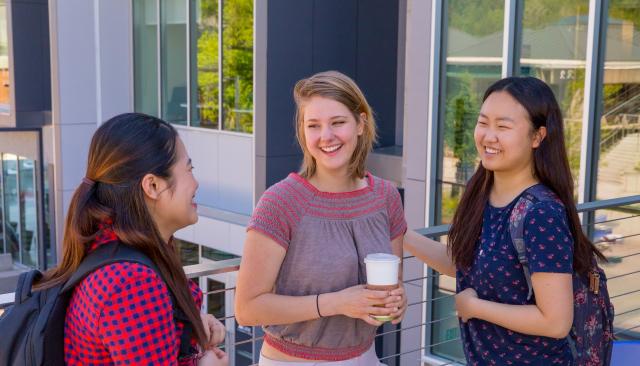 happy students with backpacks and coffee smiling and talking