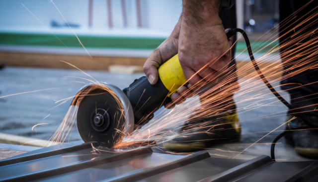sparks fly as a sheet metal worker cuts through metal