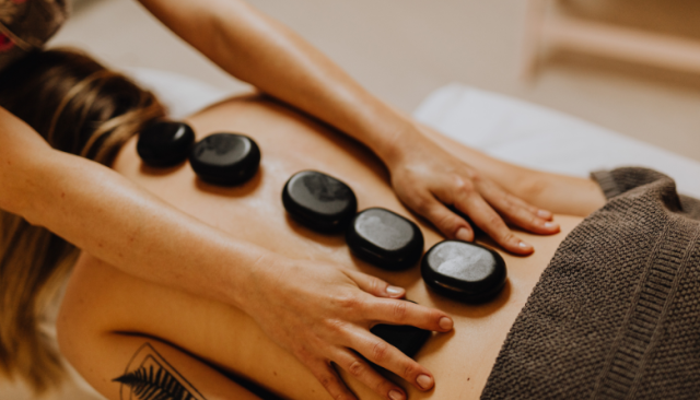 a massage therapy student practices using hot stones for a massage degree
