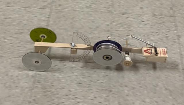 a small car made from objects like a mousetrap, a protractor, and CDs