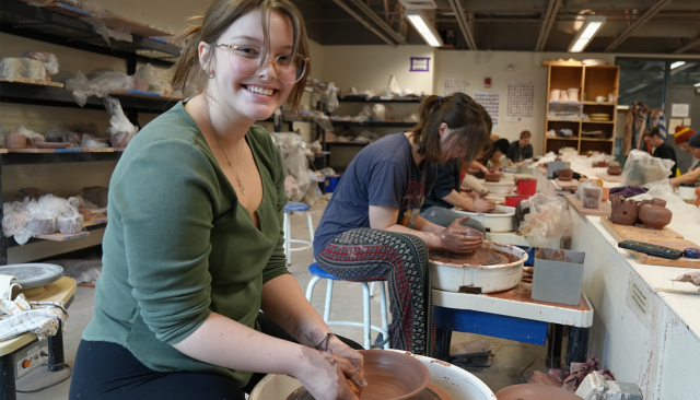 art student throwing clay at a wheel