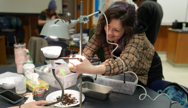 a smiling student experiments with soil in a earth science class lab
