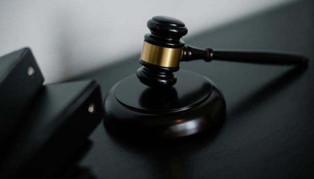 a judge's gavel resting against its soundblock on a table with legal binders