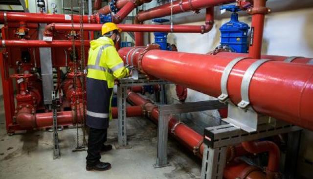 a plumber in industrial gear working on large pipes