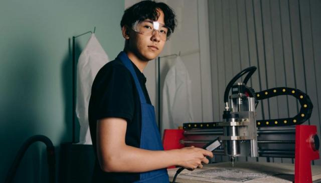 a young man in safety glasses operates an industrial machine