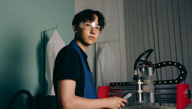 a young man in safety glasses operates an industrial machine