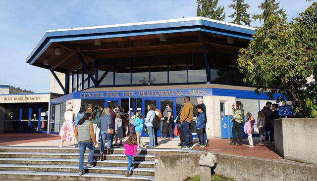 a crowd of people enter the Center for Performing Arts to see a perfomance on a sunny autumn day