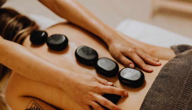 a massage therapy student practices using hot stones for a massage degree