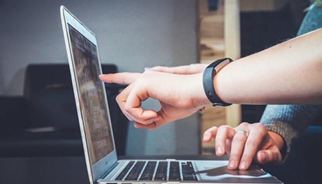 two students collaborate on an assignment, one points to a laptop