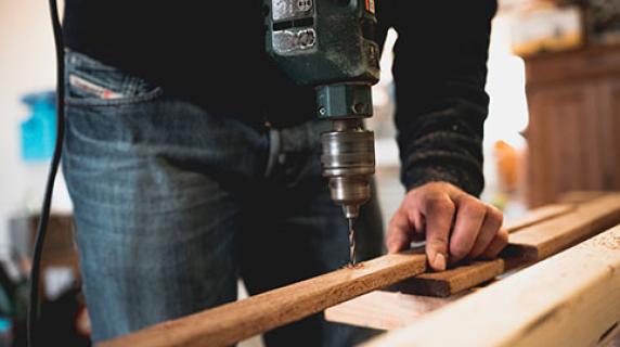 Construction worker drilling a hole in a board