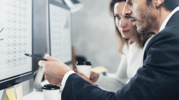 A couple of employees looking at some spreadsheets