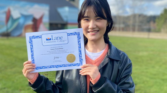 An international student, a young Japanese woman, smiles and shows off her LCC degree