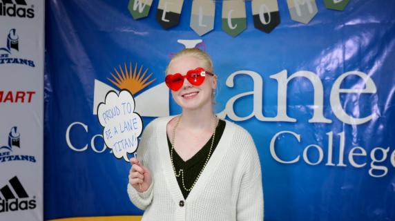 A smiling student holding a sign that says proud to be a lane titan