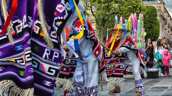 Children and families watch performers in traditional clothes at a street festival in Mexico