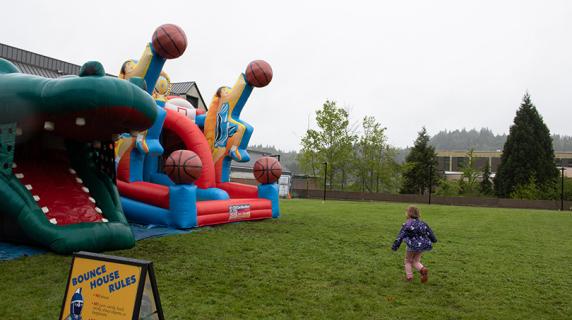 a toddler happily runs towards alligator and baskeball themed bounce slides