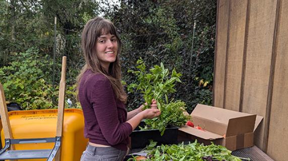 Ellie, a student worker, cleaning produce in the learning garden to donate to the food pantry