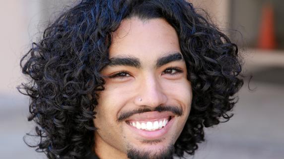 A student in a polo with black curly hair