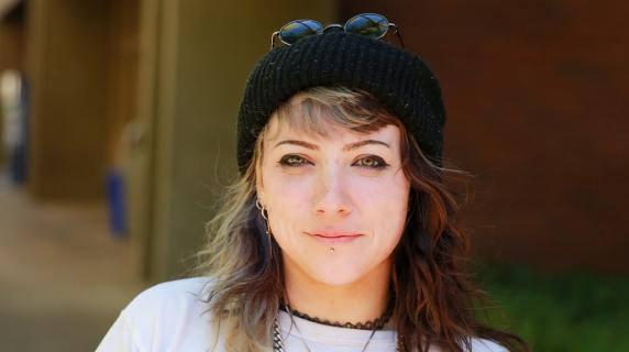 A student in a white shirt with a metal chain necklace