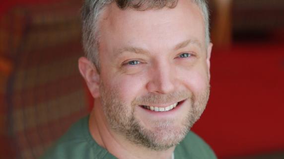 A male student with grey hair in scrubs