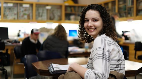 a young woman with curly hair and an excited expression smiles during a science class at Lane