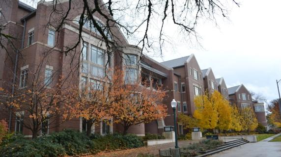 a brick building at the University of Oregon campus with pretty autumn foliage on a cloudy day 