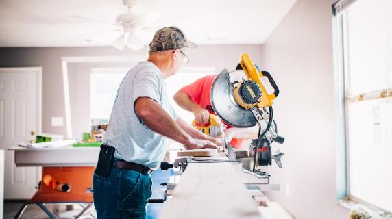 a contractor cuts tile in a home kitchen in a bright, sunny room