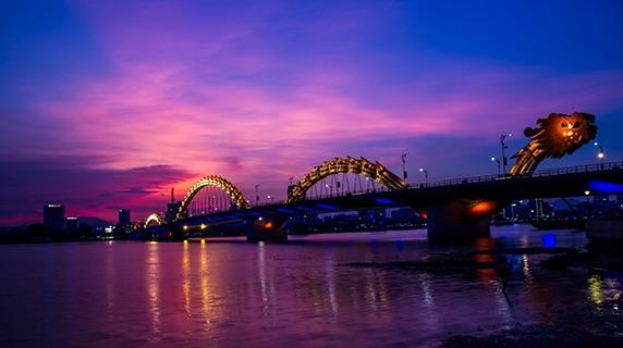 Danang Dragon bridge in Vietnam at sunset with dramatic purple/pink clouds behind it